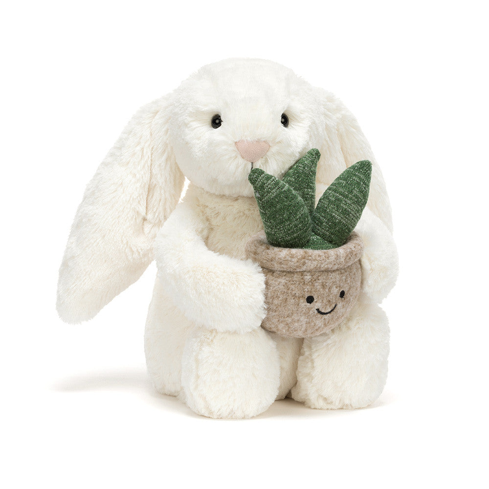 Jellycat Cream Bunny plush toy holding a green plant, soft and cuddly stuffed animal for children, detailed and adorable.