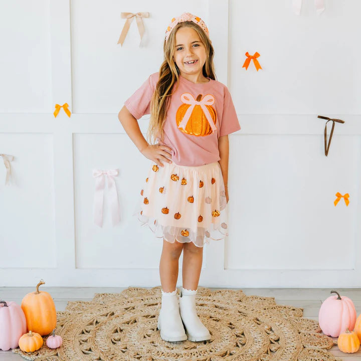 Model wearing Sweet Wink pumpkin sequin scallop tutu skirt paired with a pumpkin sequin patch short sleeve t-shirt and pearl gemstone headband.