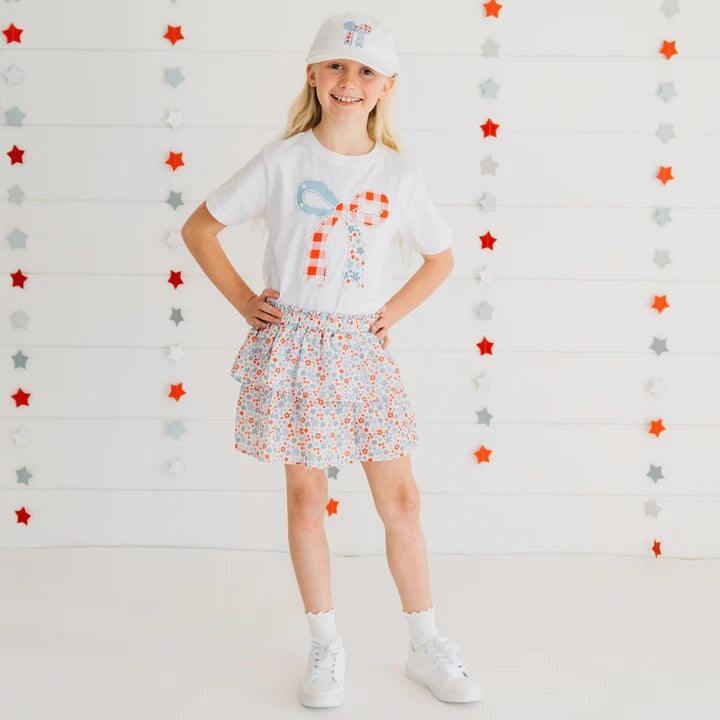 Model wearing a white short sleeve T-shirt with patchwork bow and patriotic floral design by Sweet Wink.