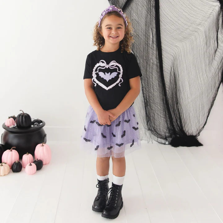 Model wearing Sweet Wink sequin bat Halloween tutu skirt with gemstone headband and short sleeve t-shirt featuring bat patch design.