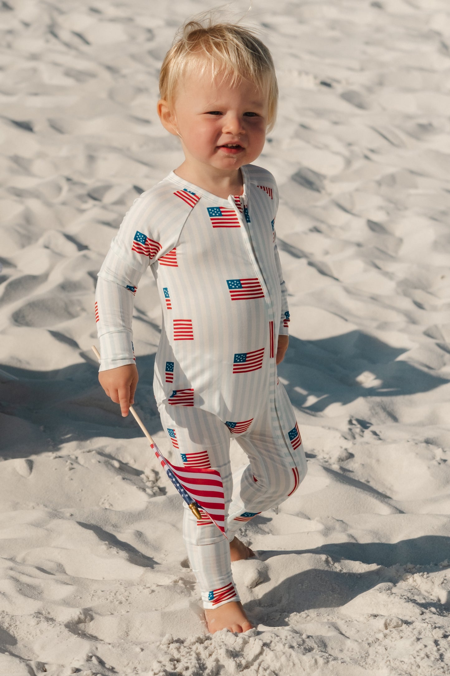 In My Jammers All American Zipper Romper displayed on a hanger, featuring a patriotic red, white, and blue design with zipper detail.