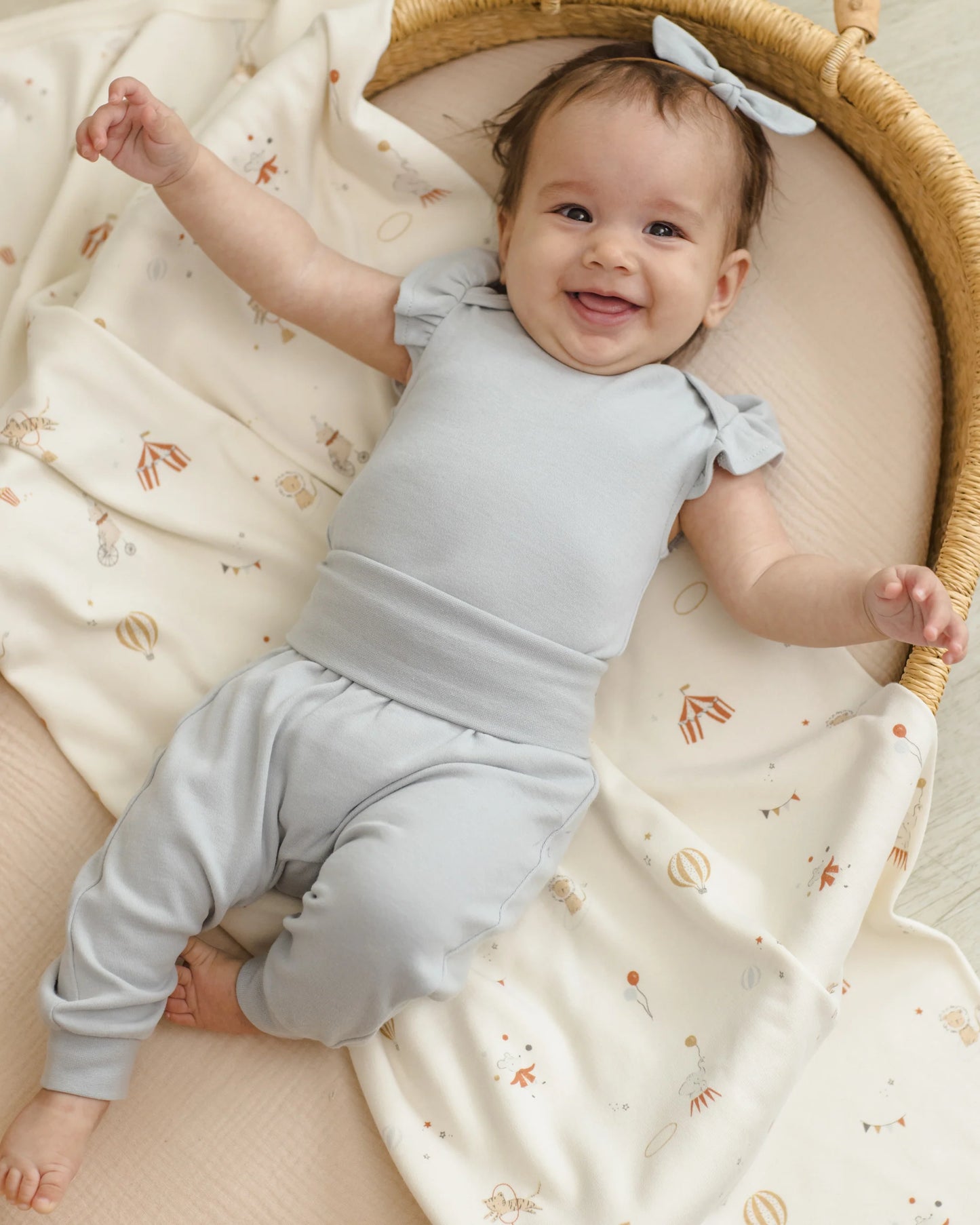 Quincy Mae Carnival Swaddle in soft fabric, shown wrapped around a baby for comfort and cozy sleep.