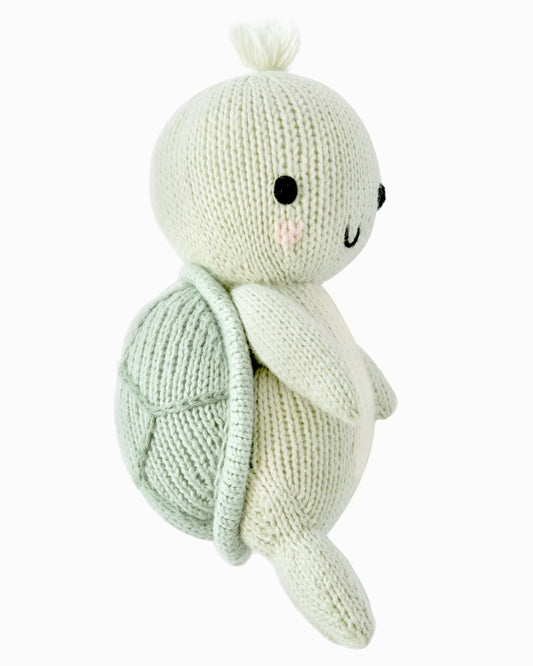 Soft plush baby sea turtle toy by cuddle + kind, featuring a green shell and gentle features, perfect for cuddling and play.