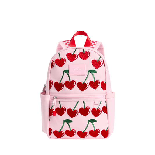 Cherry Kane mini backpack by State Bags featuring a vibrant cherry pattern, front zipper pocket, and adjustable shoulder straps.