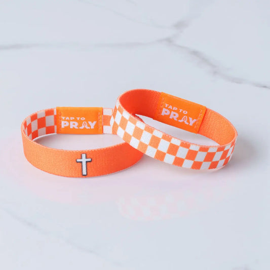Versible Tap To Pray® wristband in orange and white checkers, casual fabric band with embroidered logo and adjustable strap.