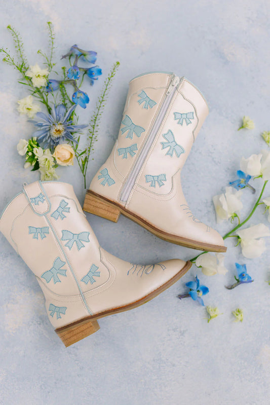 Cowgirl baby blue bow boots by Wild + Rae featuring stylish western design and decorative bows on the front.