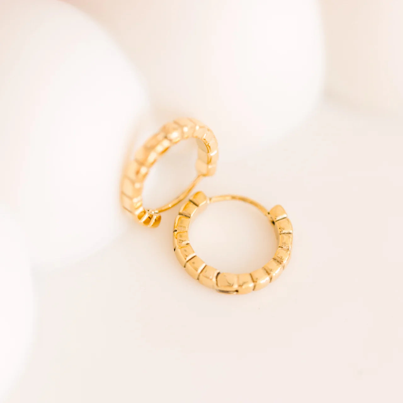 Pierced Co Keystone Huggies gold hoop earrings with textured design on a plain background.