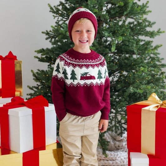 Model wearing Sweet Wink Christmas Truck Fair Isle Sweater with khaki joggers and a Christmas tree beanie, festive holiday outfit.