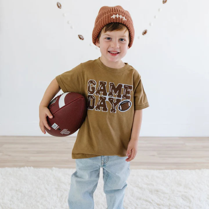 Model wearing Sweet Wink Game Day Patch mocha short sleeve T-shirt with football lace patch and matching beanie.