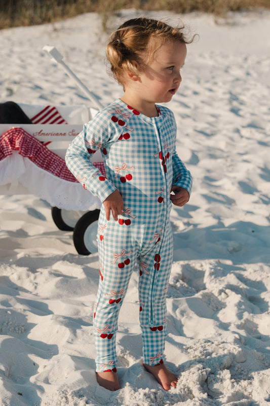 In My Jammers Little Cherry Zipper Romper in pink with cherry print, front zipper closure, and short sleeves, laid flat on a white background.