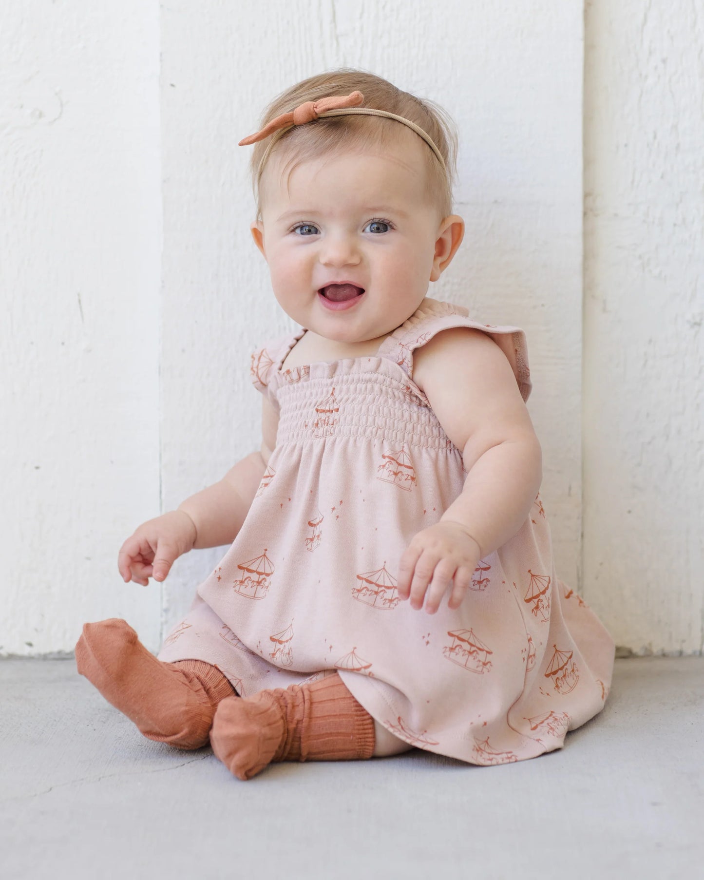 Quincy Mae Carousel Smocked Jersey Dress displayed on a child, featuring a soft, stretchy fabric with smocking detail and a playful, colorful pattern.