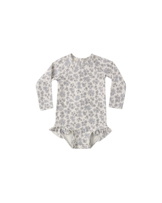 Blue floral Olivia rashguard one-piece swimsuit by Quincy Mae, featuring a vibrant floral pattern and long sleeves for sun protection.