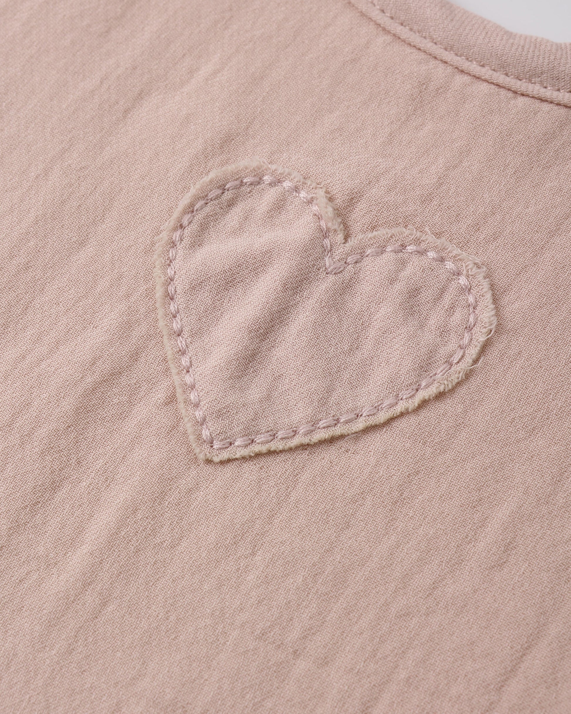 Close-up of Quincy Mae blush woven tie bib showing detailed fabric and delicate design for baby accessories.