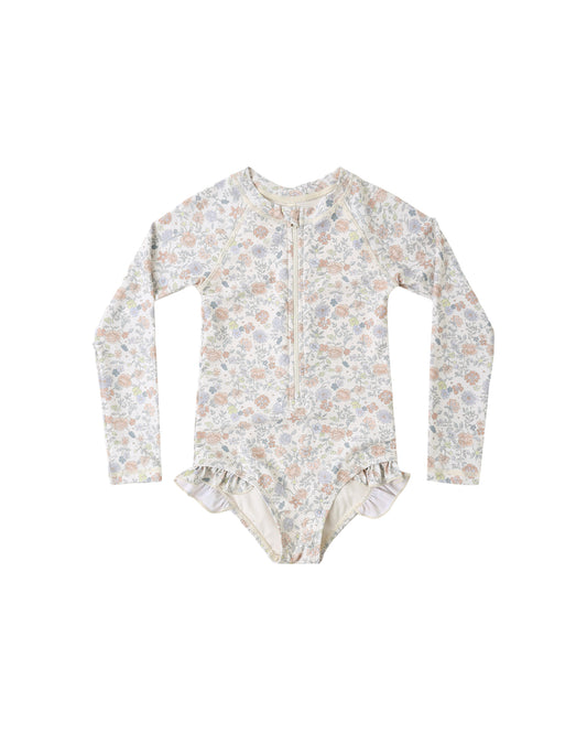 Rylee & Cru Bloom rashguard one-piece swimsuit in ivory, featuring a floral pattern and long sleeves for sun protection.