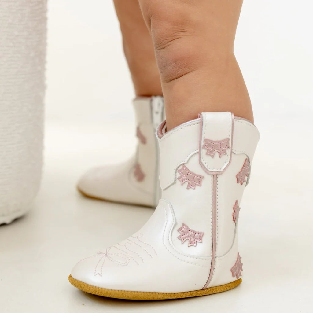 Cute cowgirl bow baby booties by Wild + Rae with adorable bows, soft fabric, and stylish design for little feet.