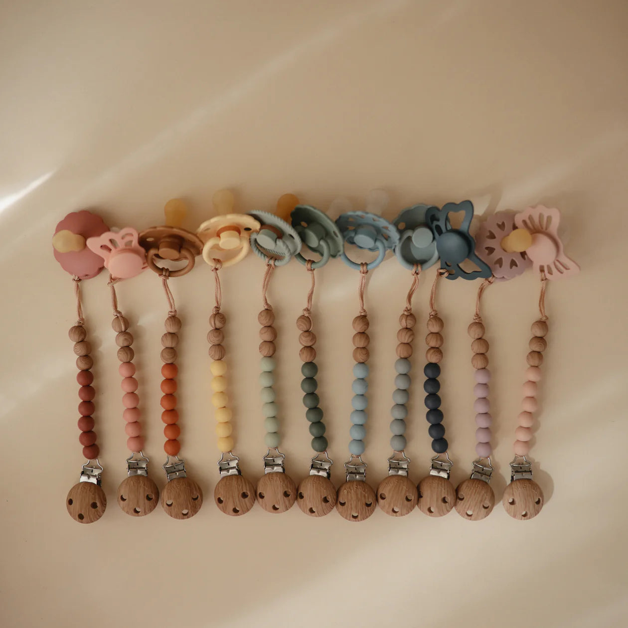 Mushie silicone pacifier clip with colorful beads and clip attachment, designed to keep pacifiers secure and accessible for babies.