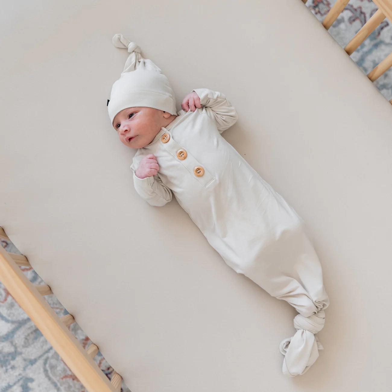 Kyte Baby knotted gown with matching hat set for infants in oat color, soft cotton fabric, comfortable and stylish baby clothing.