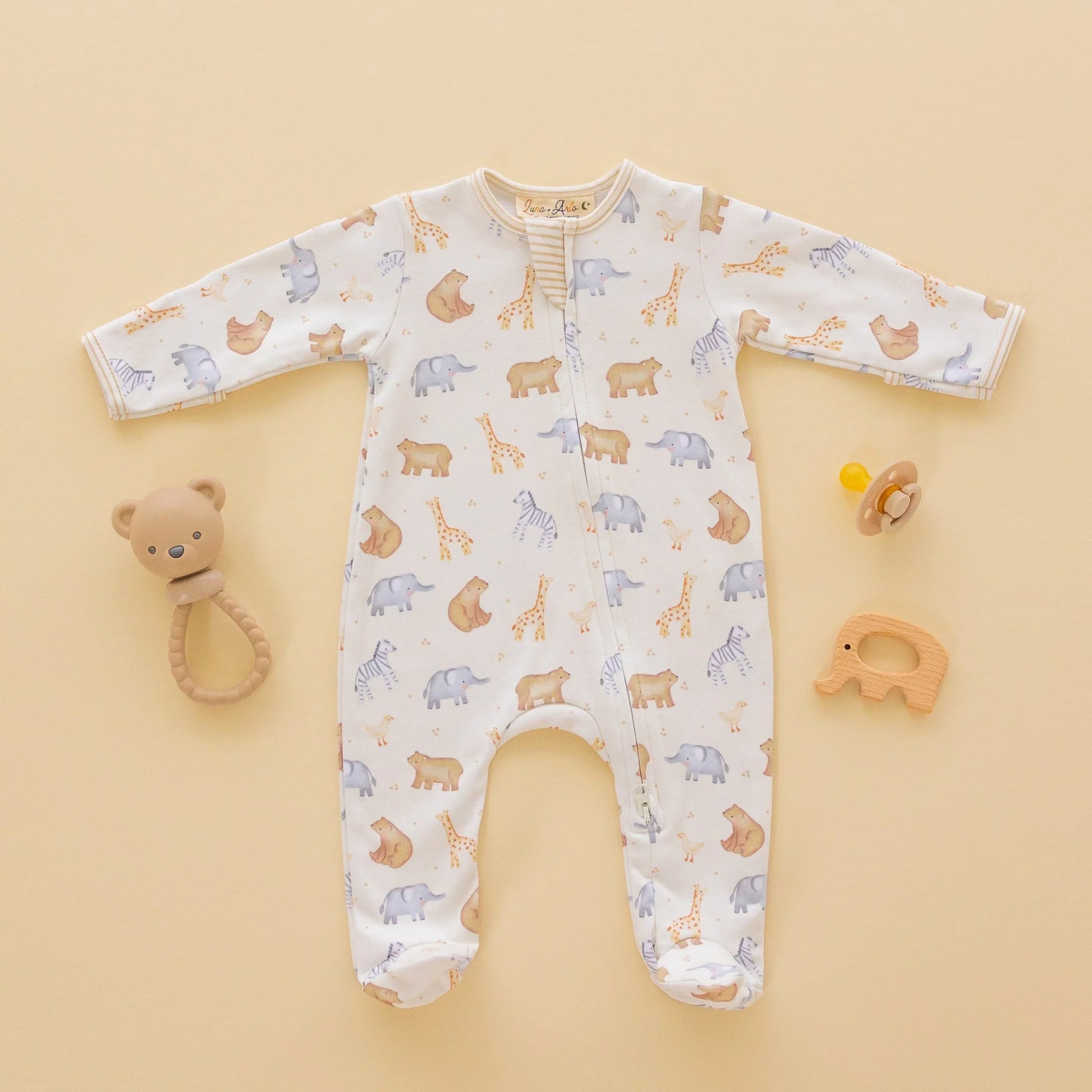 Luna + Arlo Safari Zip Footie for babies, soft fabric with zipper closure, featuring playful safari animal prints on a neutral background.
