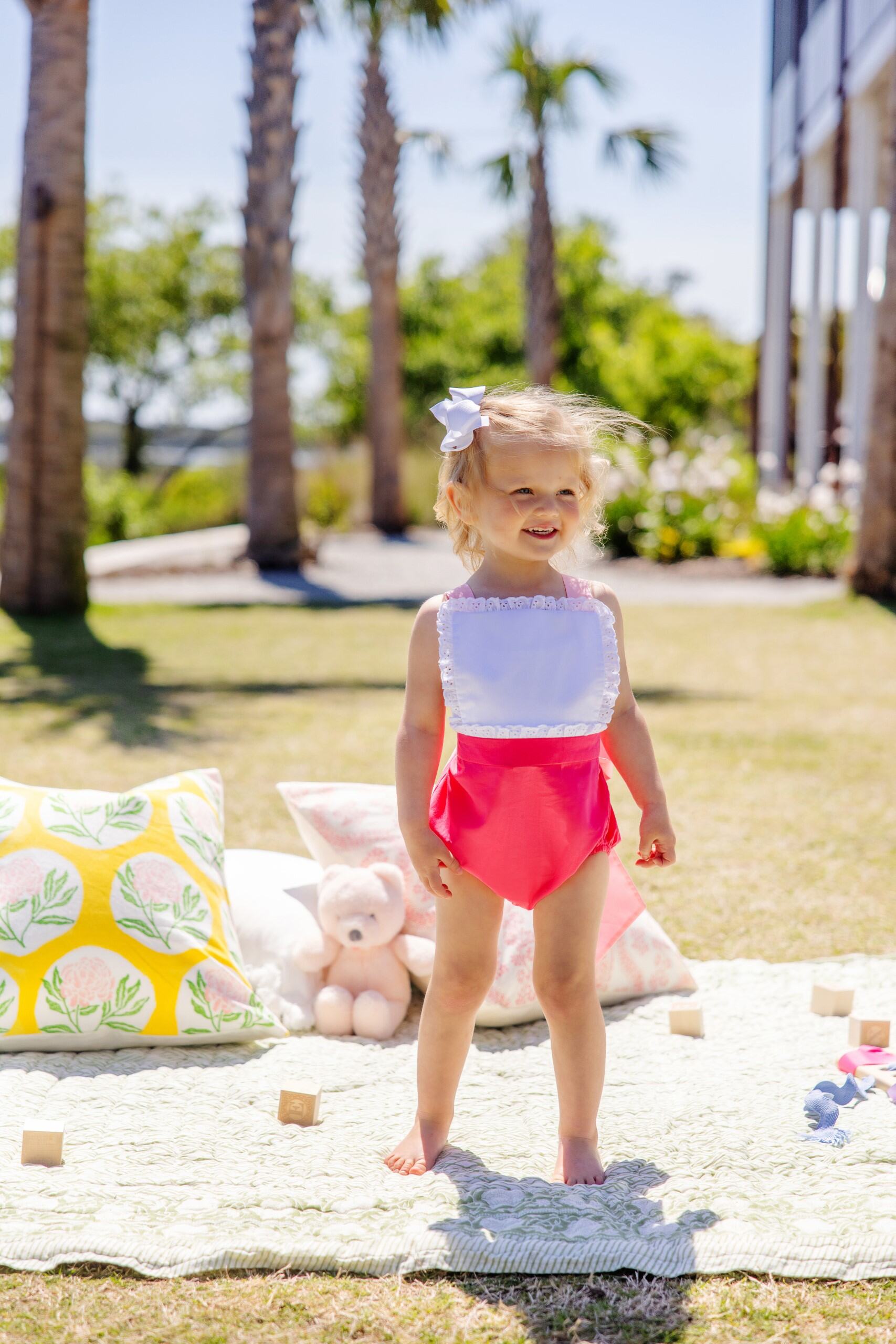Pink Sally sunsuit with palm springs punch and sandpearl details from The Beaufort Bonnet Company, featuring a sleeveless design and playful pattern.