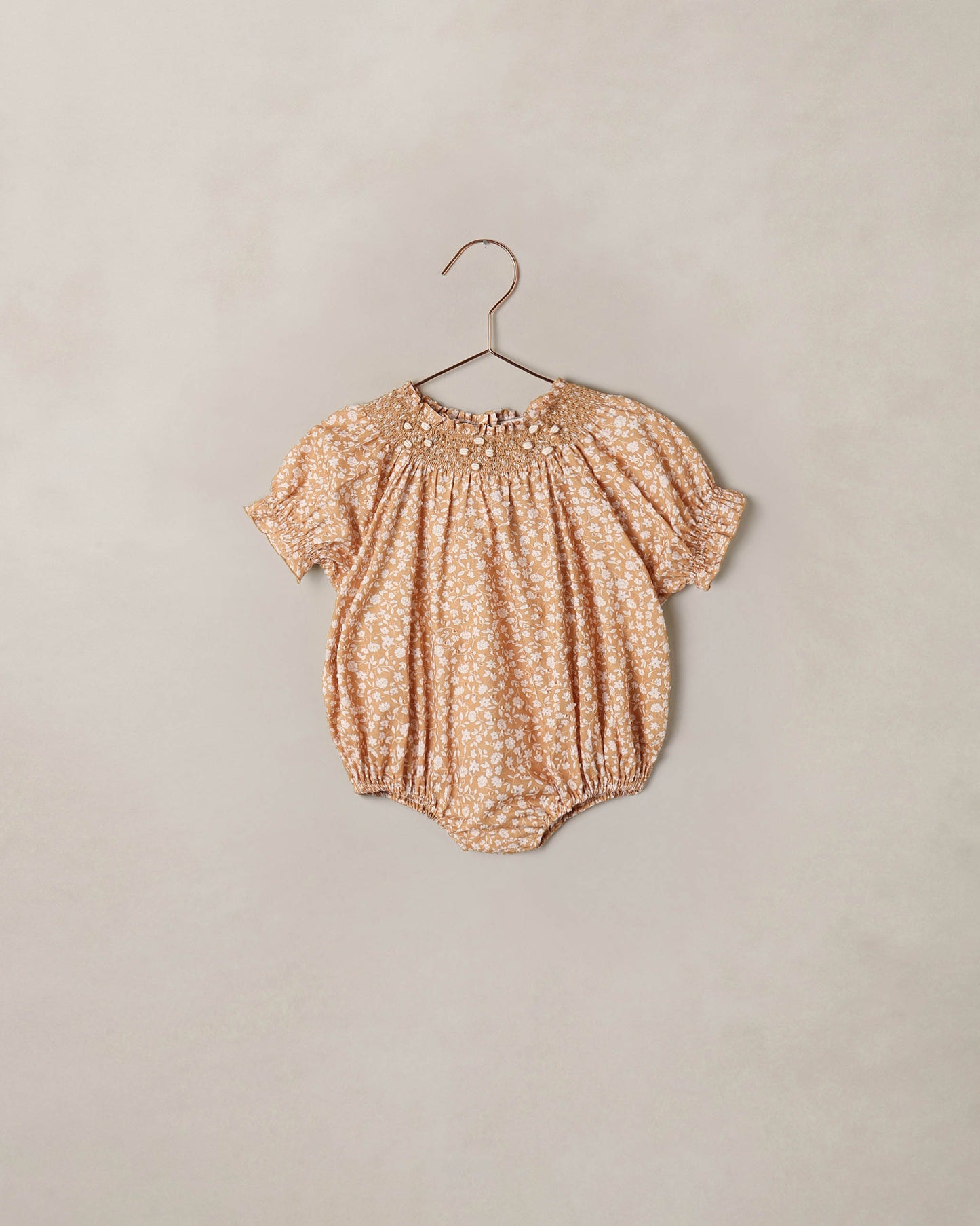 Noralee Golden Meadow Maddie Romper displayed on a hanger, featuring a floral pattern and soft fabric ideal for warm weather.