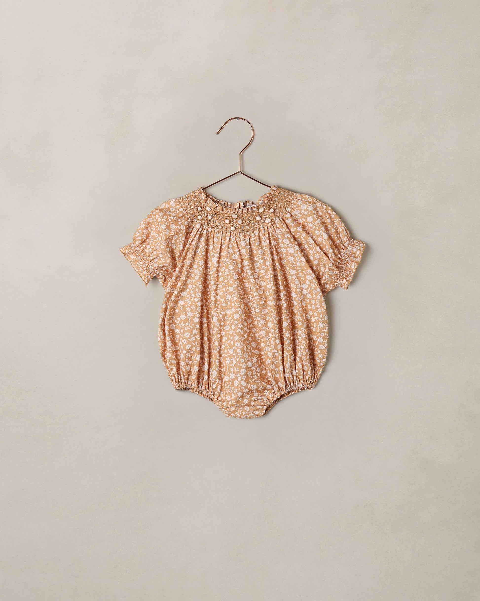 Noralee Golden Meadow Maddie Romper displayed on a hanger, featuring a floral pattern and soft fabric ideal for warm weather.